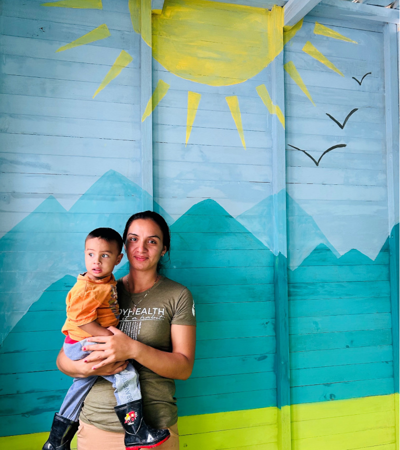 woman holding her son in front of a painted wall